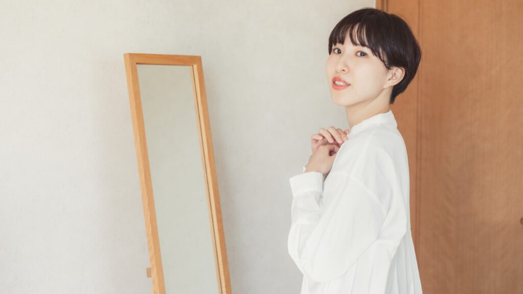 鏡の前でシャツを着る女性