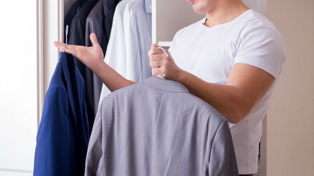 ２つのスーツを手に取る男性